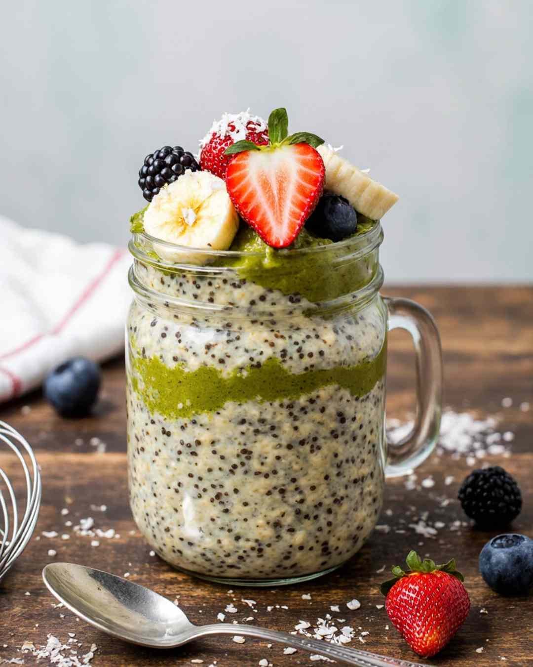 Final prepared Matcha Overnight Oats Recipe in a mason jar with fresh fruit toppings and coconut flakes.
